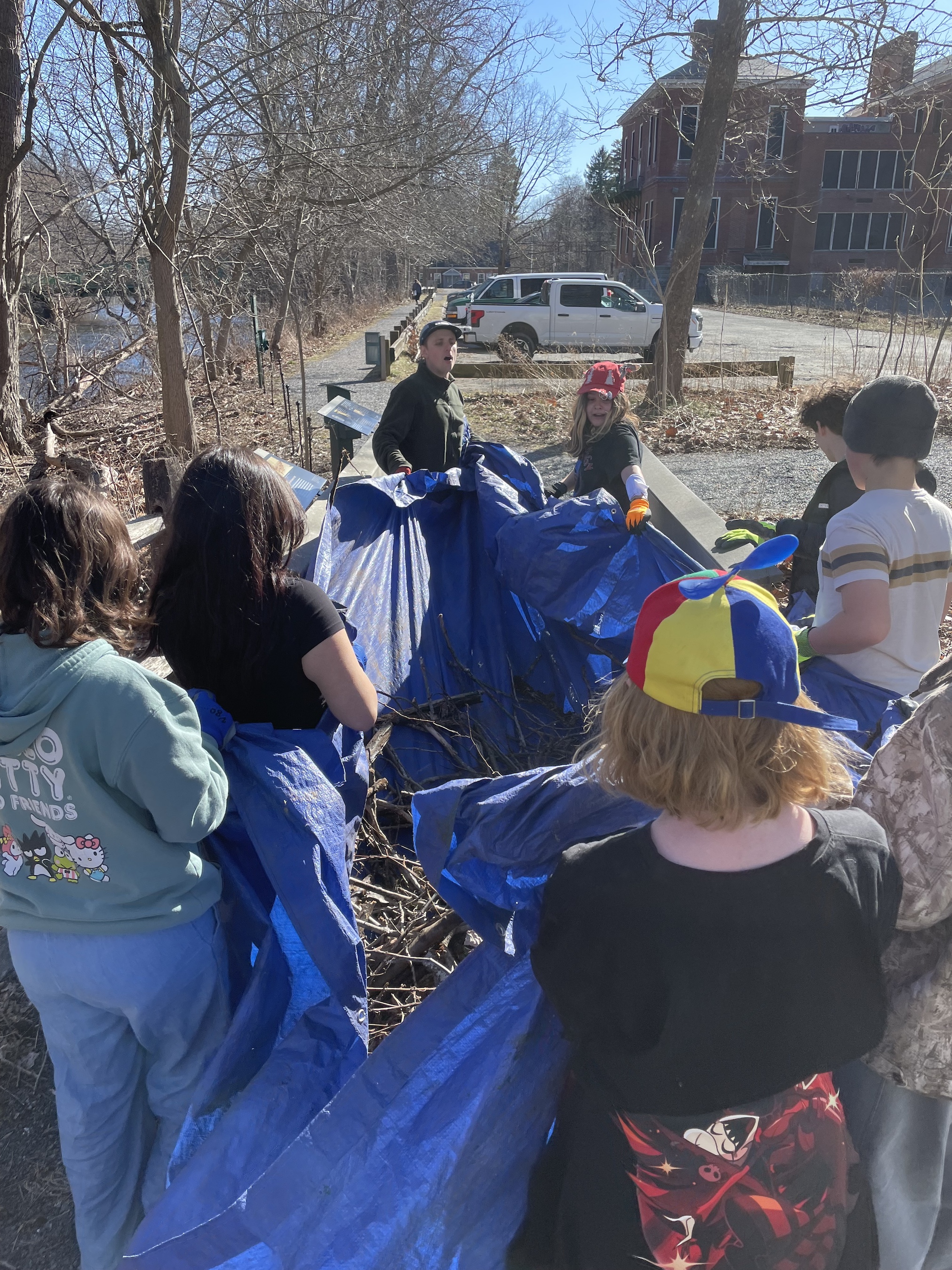 Students yanked large sticks and branches from the compost pile and put them on a large tarp. It took the entire group to transport the tarp to the riverbank area.